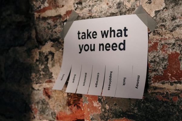 A motivational note offering positive qualities taped to a brick wall.
